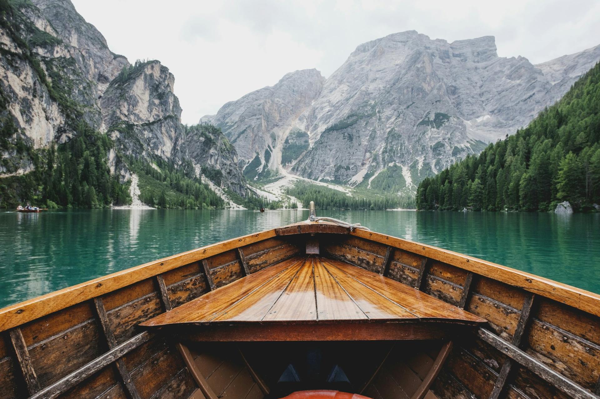 Barco de madeira em lago cercado por montanhas